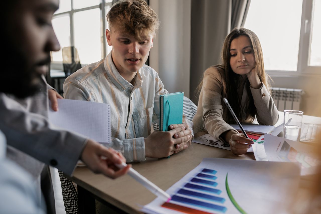 home-services-004 A diverse team of young professionals engaged in a business meeting analyzing graphs and data.